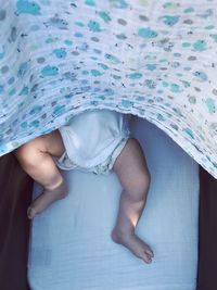 Low section of baby girl relaxing on bed at home