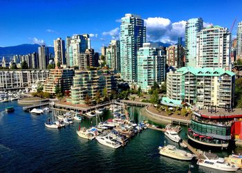 High angle view of boats at port by buildings in city