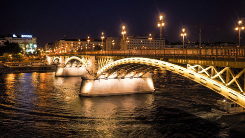 Illuminated margaret bridge over danube river against sky in city at night