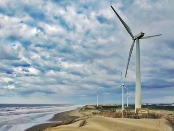 Windmills on beach against sky
