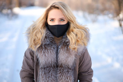 Portrait of young woman standing in snow