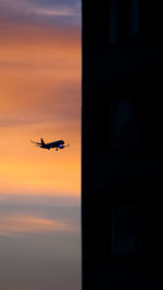Silhouette airplane flying against sky during sunset