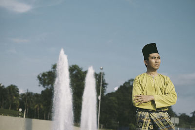 Portrait of young man standing against fountain