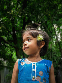 Portrait of young woman standing against trees