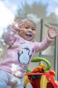 Portrait of cute baby girl with arms raised