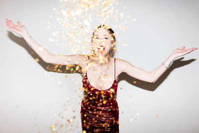 Portrait of woman with arms raised standing against white background