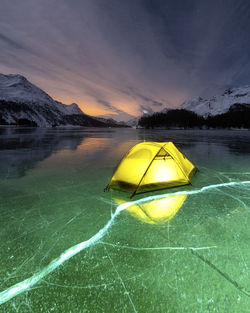 Yellow floating on lake against sky during sunset