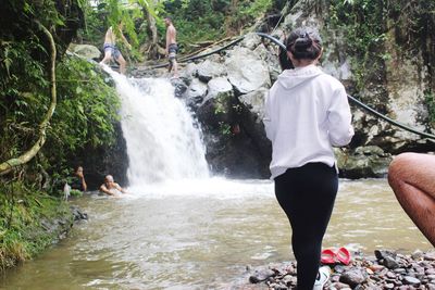 Rear view of man standing on rock in forest