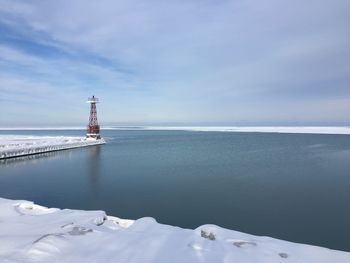 Lighthouse by sea against sky during winter