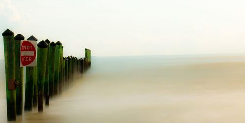 Road sign by sea against sky