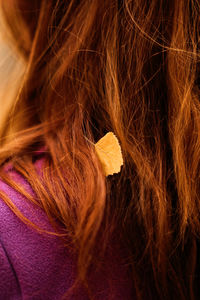 Autumn portrait of candid beautiful red-haired girl with fall leaves in hair.