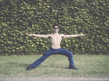 Shirtless young man stretching on grassy field