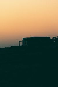 Silhouette built structure against orange sky