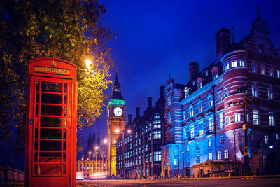 Telephone booth with illuminated city buildings in background