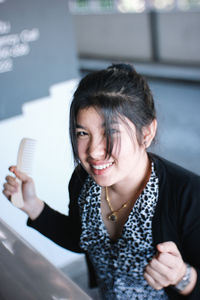 Portrait of a smiling young woman holding camera