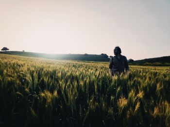 Rear view of man standing on field against clear sky