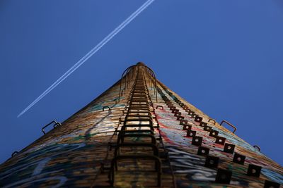 Low angle view of graffiti on tower against clear blue sky