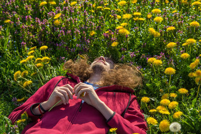 High angle view of man lying by yellow flowers on field