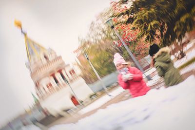 Blurred motion of people on umbrella against sky