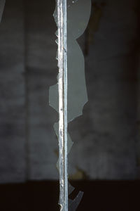 Close-up of frozen railing against window during winter