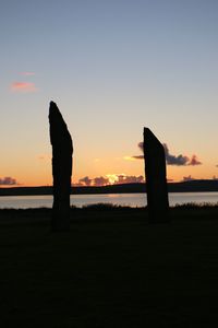 Silhouette built structure against sea at sunset