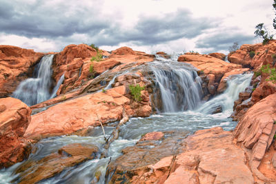 Scenic view of waterfall against sky