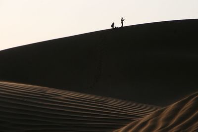 Low angle view of silhouette man walking against clear sky
