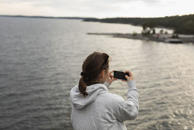 Woman taking photo at sea