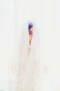 Woman hiding behind white curtain