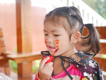 Close-up of cute girl applying paint on face