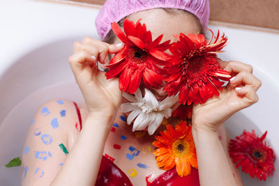 Close-up of woman holding red flower in bathtub