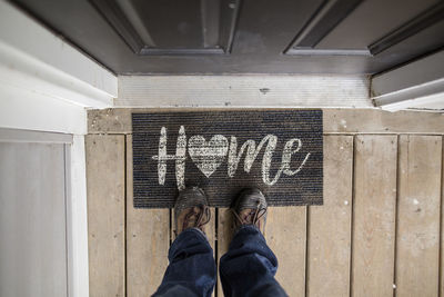 Close-up of person standing on doormat at the entry of a home