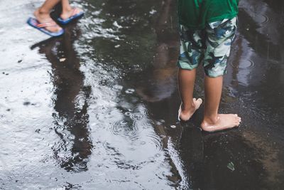 Low section of boys playing on wet street