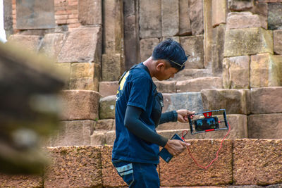 Side view of boy holding stone wall