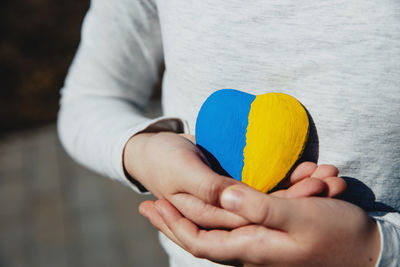 Small little kid hold heart with ukraine flag. child stand for ukrainians. stop war, agression