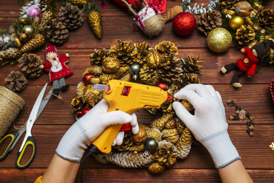Cropped hand of woman holding christmas decorations on table