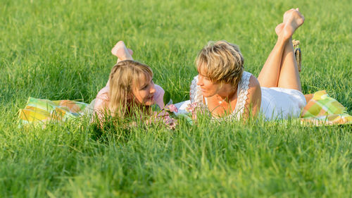 Friends talking while lying on grassy field