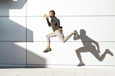 Young athlete running against white wall