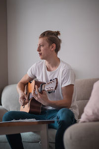 Candid portrait of a young singer playing an acoustic guitar and singing in a hymn book 