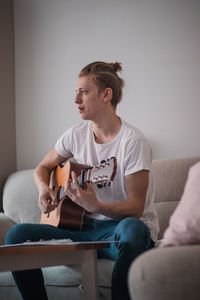 Young man looking away while sitting on sofa