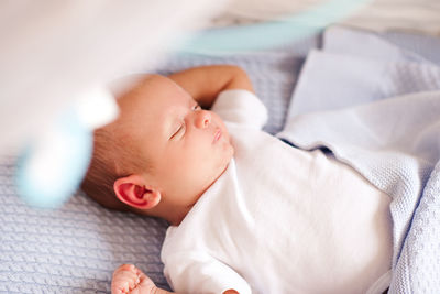 Cute baby boy sleeping on bed at home