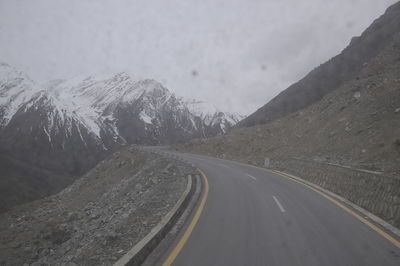 Road by mountains against sky during winter