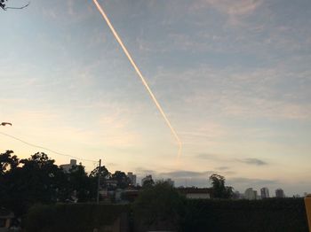 Low angle view of vapor trails in sky at sunset