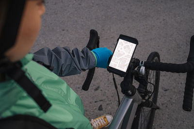 From above anonymous courier examining route on gps map before riding bicycle on city street