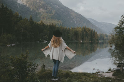 Rear view of woman standing at lakeshore