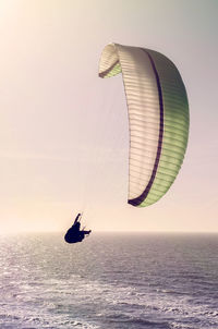 People in sea against sky during sunset