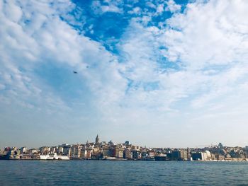 City at waterfront against cloudy sky