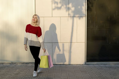 Portrait of young woman standing against wall