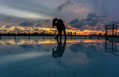 Reflection of woman in sea at sunset