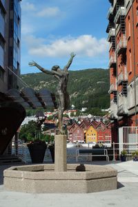 Statue amidst buildings in city against sky